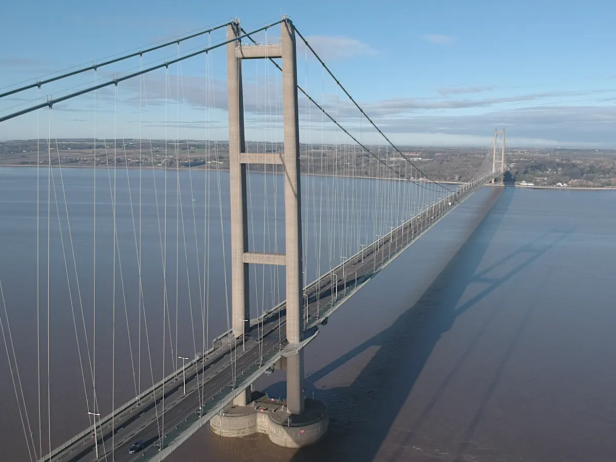 Aerial view of a long suspension bridge crossing a wide estuary