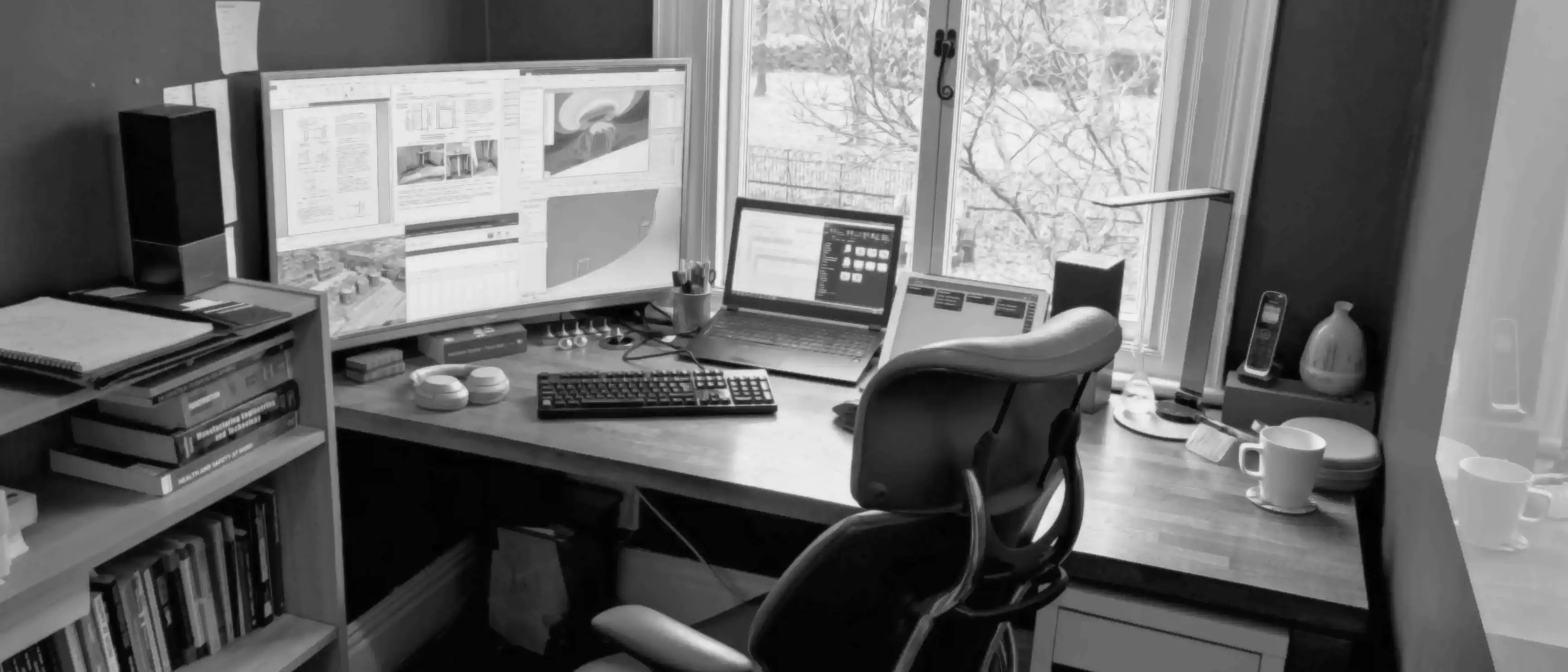 Desk workspace with engineering drawings and CAD open on screens in a home office