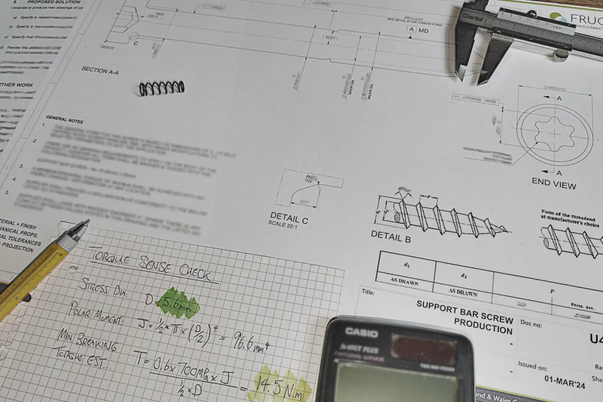 Engineering brief, sketches and calculations laid out on a desk during early-stage design scoping